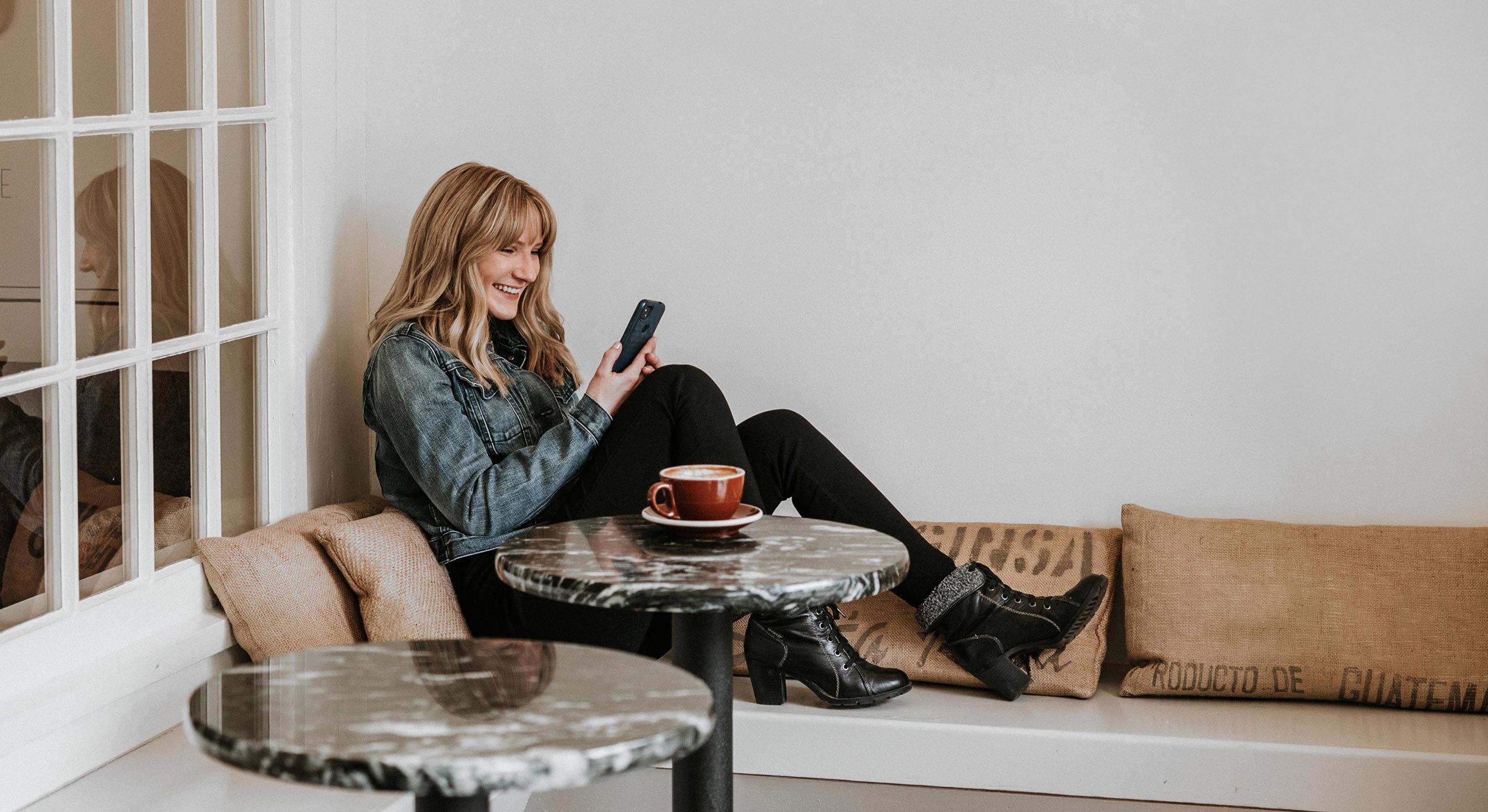 Photo of Aimee sitting on a couch working on a mobile device